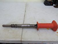 Full length view of the Remington Ram Set nail setter showing metal shaft and orange handle.