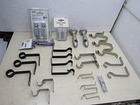 Lot of assorted shelf and curtain rod brackets of various sizes and finishes, arranged flat on a white background.