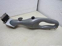 Handheld gray Grill Daddy brush with metal bristles and integrated steam control buttons.