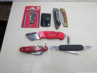 Photo showing all seven pocket tools laid out on a light surface, highlighting different blade and handle styles including keychain multi-tool in original packaging with leather pouch.