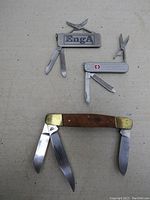 Overview of the three pocket tools laid flat showing all blades extended for size and feature comparison.