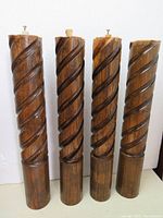 Four hardwood furniture legs with spiral carved design shown upright against a white background.