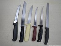 Six cutting knives arranged in a row showing blade and handle details on a neutral surface