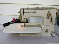 Full side view of vintage Bernina Record sewing machine with table extension attached and power cord visible. Light on the machine is turned on.