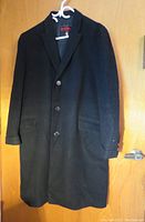 Full front view of the vintage black cashmere men's coat by Peter Anallo, buttoned, showing lapel collar, front pockets, and sleeve buttons.