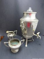 Front view of vintage electric samovar with sugar and milk containers on either side, showing glass lid and spigot detail
