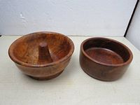 Both vintage wooden bowls displayed side by side on a white surface against a white background. One bowl features a central cone shape, the other a simple rounded basin shape with smooth edge.