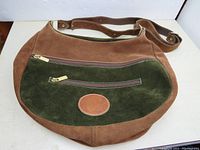 Front view of vintage brown and green suede purse showing two zippered pockets and leather patch