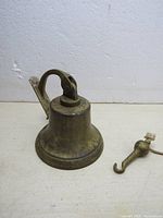 Front and side view of the vintage brass bell showing the hanging mount and pull cord.