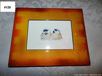Two framed bird prints with pairs of birds, orange shaded frames, on decorative background