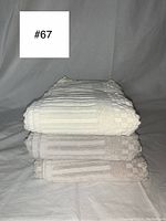 Three folded towels stacked, showing the textured checkered and striped pattern, in neutral tones.