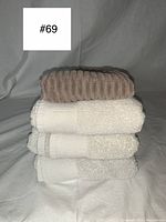 Stack of 4 towels shows three grey plush towels and one white towel underneath.
