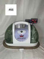 Front view of Bissell Little Green TurboBrush upholstery cleaner showing transparent green water tanks and flexible hose attachment at the base.