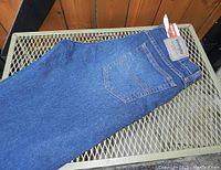 Side view of men's Wrangler jeans showing dark blue denim fabric, wide leg, and back pocket with Wrangler tag.
