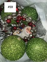 Bagged collection showing green glitter balls, red and silver jingle bell garland, Santa face and nutcracker figurines.