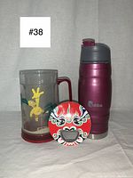 Items arranged against white backdrop showing three objects: Simpsons Homer beer mug, Bubba travel mug, double-sided bottle opener.