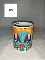 Front view of ceramic mug showing cartoon zombie Marylin Monroe face with blue skin, orange hair, and exaggerated eyes.