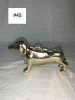 Side view of gold metal dachshund tape dispenser showing its length and the tape roll inside.