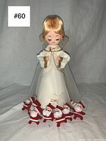 Photo showing the full set including the wind-up angel with white gown and eight small flocked Santa Claus figurines arranged in front.