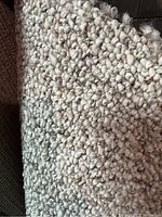 Close-up of beige Berber carpet remnant showing thick looped yarn texture.