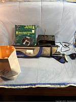 Overview photo showing the full lot including golf bag with clubs, digital putting cup and its box, and a partial view of the golf balls bag.