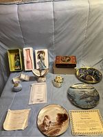 Full lot overview on sofa showing music boxes, plates, figurines, certificates