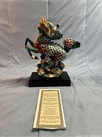 Front view of the colorful ceramic Qilin statue on black rectangular base with story card in front