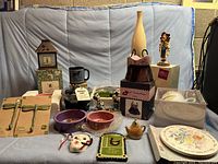 Wide view of all whimsical gifts arranged on blue couch showing variety of items including pet bowls, Disney figurines, decorative plates, and hooks.