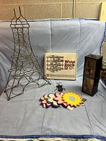 Overall view of all items in the lot including the Eiffel Tower shaped metal wine rack, boxed wooden expandable wine rack system, flower-shaped wine coasters, and wooden wine box carrier.
