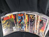 Bulk of comic books featuring Hulk series and other titles shown in plastic bags on black background