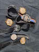 Lot of seven mixed style watches including vintage mechanical and modern digital Timex watch on black background.