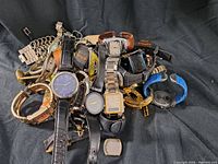 Lot of multiple vintage and used wristwatches piled together showing mixed condition and types including metal and leather bands.