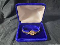 Bulova women's wristwatch inside blue velvet box with white satin lid interior.