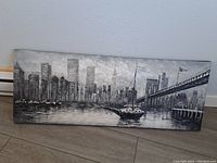 Full view of grayscale cityscape painting showing skyline, boats on water, and large suspension bridge.