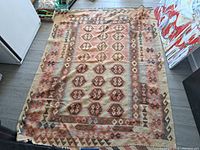 Full view of large rectangular carpet with a predominantly brown, pink, cream, and blue geometric pattern on floor