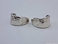 Front view of both wide curved sterling silver earrings with textured hammered look.