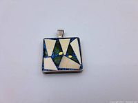 Front of square multi-stoned sterling silver pendant with geometric patterned inlay in blue, white, and green stones