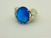 Front view of sterling silver ring with large oval faceted blue stone and decorative silver details