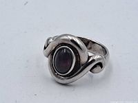 Close-up front view of sterling silver ring with an oval red stone.