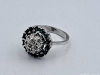 Front view of the vintage sterling silver ring showing white stones in the center dome with surrounding green stones.