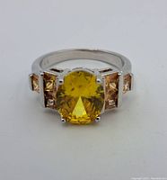 Front view of the sterling silver ring with large oval yellow topaz and smaller light brown side stones.