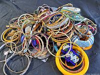 Pile of assorted colorful and metallic costume jewelry bracelets and bangles showing variety of shapes and designs.