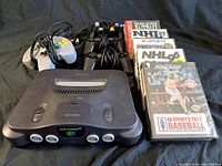 Nintendo 64 console, four controllers, and multiple sports video game cases.
