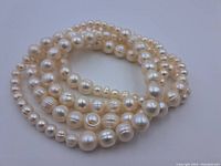 Another view of the necklace displaying a coiled positioning of the pearls, emphasizing the shape and surface wear.