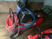 Side view of the red 26 gallon air compressor with motor, hoses, wheels, and handle visible.