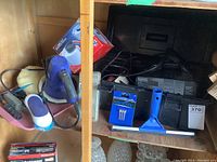 Additional angle showing assortment of tools, polisher, beverage holder box, and emergency kit items arranged on the shelf for clarity of individual parts.