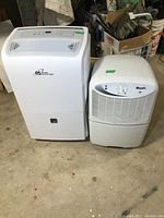 Photo showing both Wood's 25 and Royal Sovereign dehumidifiers side by side on concrete floor.
