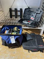 Photo of the lot showing Rapala electric fillet knife in molded case, soft-sided blue bag full of fishing tackle and artificial bait, a black ColdHeat seat pad with charger pouch, all arranged on a wire shelf.
