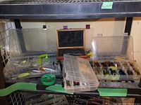 Overall view of 4 plastic organizers filled with assorted fishing lures and baits, and a wooden case with a pocket tool