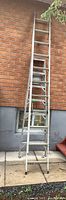 Full view of the 20-foot aluminum extension ladder extended against brick wall showing condition and length.
